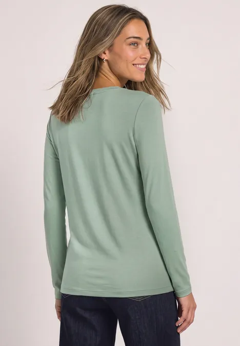 Basic Shirt mit U-Boot-Ausschnitt eucalyptus green Frau im mintgrünen Langarmshirt und Jeans, Blick seitlich über die Schulter.