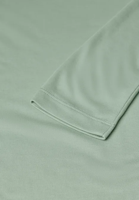 Basic Shirt mit U-Boot-Ausschnitt eucalyptus green Nahaufnahme eines hellgrünen Kleidungsstücks mit sichtbarer Naht und Ärmel.