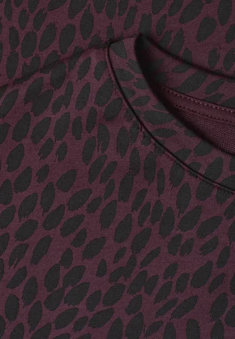 Nahaufnahme eines burgunderfarbenen Shirts mit schwarzem, organischem Muster und Rundhalsausschnitt.