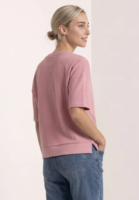 Shirt met ronde hals en structuur vintage blush Een vrouw in profiel draagt een roze trui met korte mouwen en een blauwe spijkerbroek.
