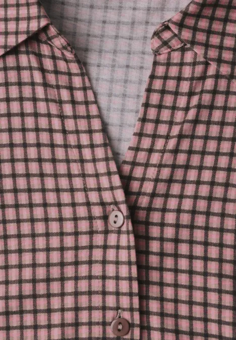 Nahaufnahme einer rosa-schwarzen karierten Bluse mit Knopfverschluss.