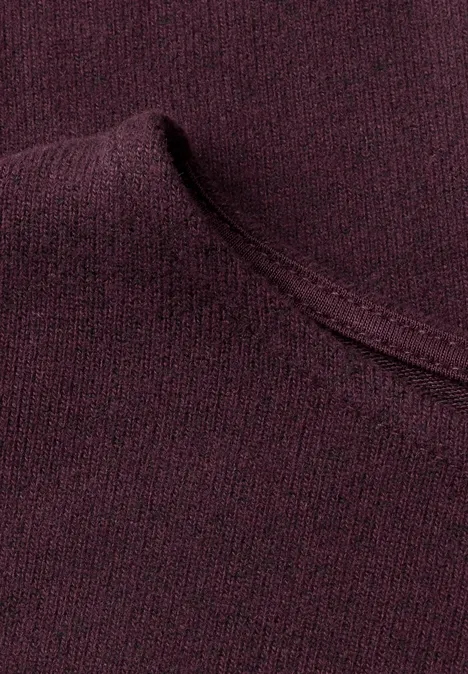 Nahaufnahme eines weinroten Strickpullovers mit sichtbarer Naht