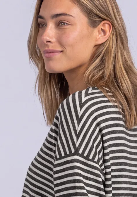 Langarm Shirt mit Elastikbund black coffee mel. Eine junge Frau mit langem, hellem Haar trägt ein gestreiftes Oberteil und schaut seitlich lächelnd.
