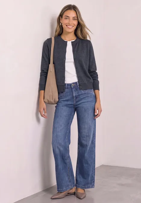 Langarm Jacke im Strick-Look mit Rundhals indigo night mel. Frau lächelt in Jeans, weißem Shirt und dunkelgrauer Jacke mit Schultertasche gegen weiße Wand.