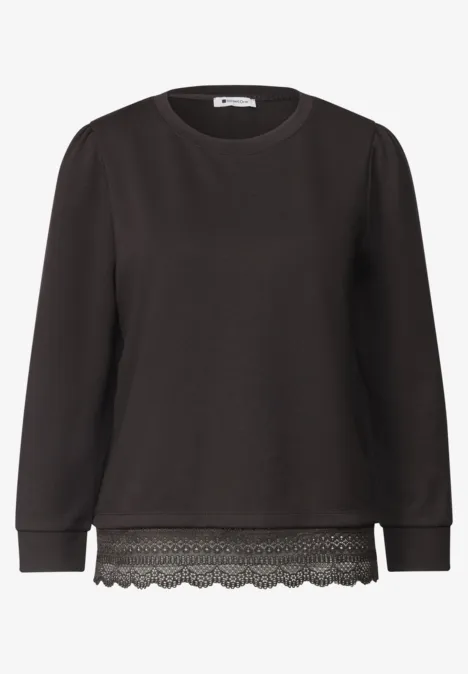 Schwarzer Pullover mit Rundhalsausschnitt, langen Ärmeln und Spitzenbesatz am Saum.
