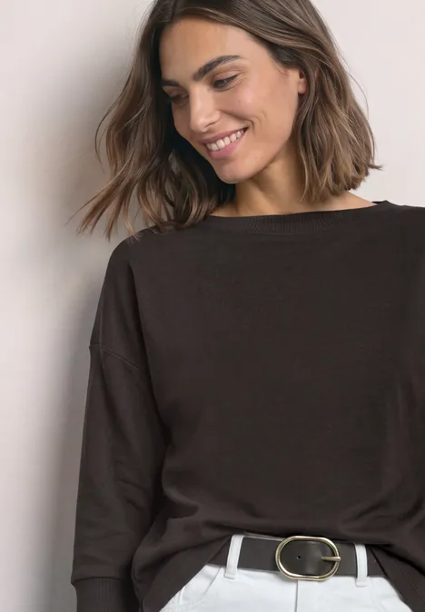 3/4-Arm Shirt mit Rippstrukturdetails black coffee Eine junge Frau mit braunem Pullover und Gürtel lächelt leicht und blickt zur Seite.