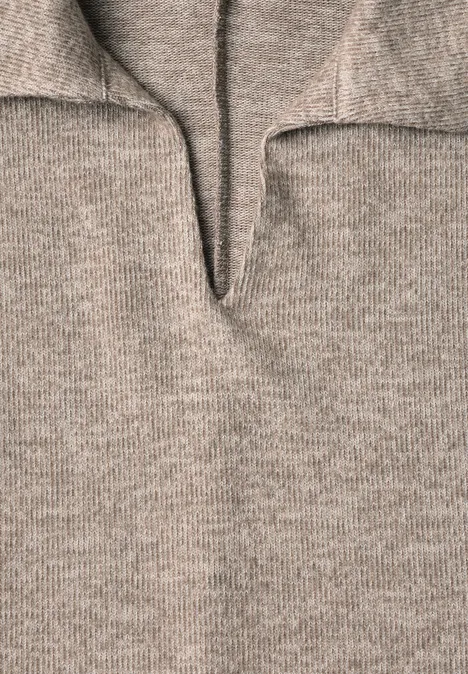 Nahaufnahme eines beige-grauen Strickpullovers mit V-förmigem Ausschnitt und aufgestelltem Kragen.