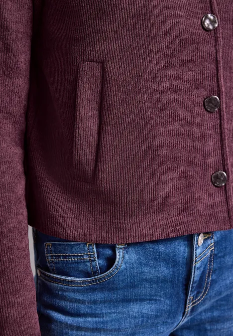 Cardigan en maille bordeaux à boutons et poche, porté avec un jean bleu.