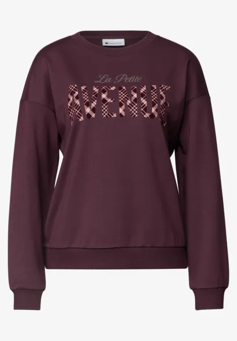 Ein weinrotes Sweatshirt mit Rundhalsausschnitt und 'La Petite Merci' auf der Brust.