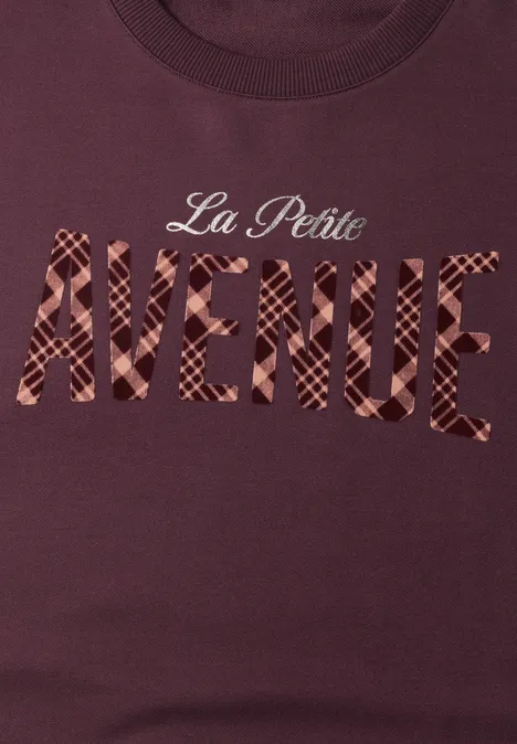 Dunkelrotes T-Shirt mit Schriftzug 'La Petite AVENUE' in karierter Optik.