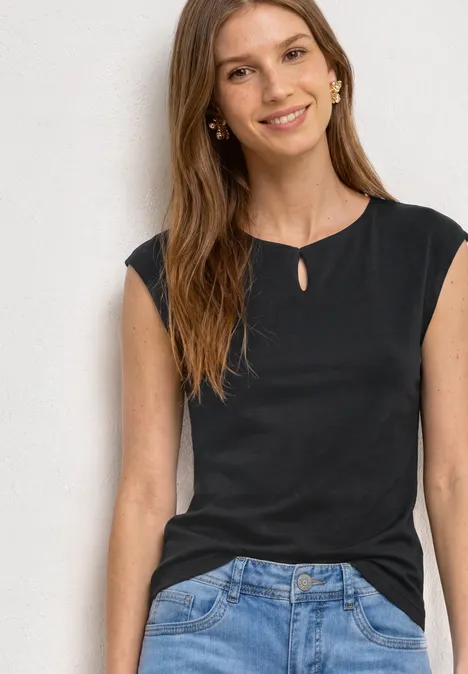 Shirt met afhangende schouders en uitsnijding Black Vrouw in zwart mouwloos shirt en spijkerbroek voor witte muur