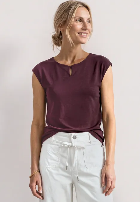 Shirt met afhangende schouders en uitsnijding rustic rouge Vrouw in bordeaux mouwloos shirt en witte high waist-jeans voor een lichte achtergrond