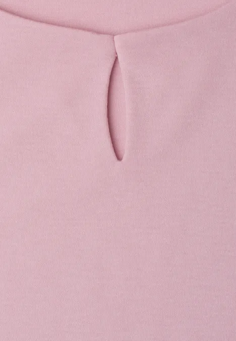 Gros plan sur un haut rose avec petite fente au niveau du col rond.
