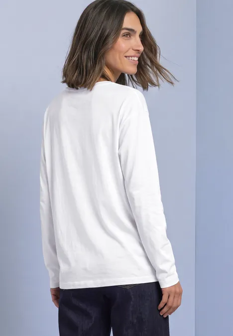 Effen shirt met lange mouwen White Vrouw met halflang haar draagt een wit T-shirt met lange mouwen, staat in zijzicht en kijkt over haar schouder.