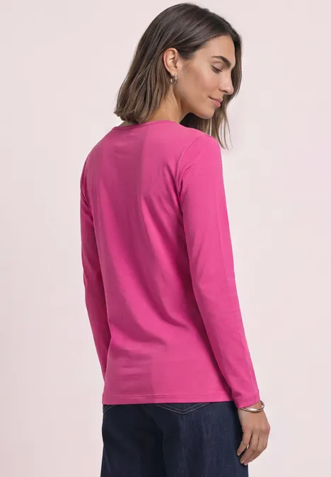 Basic Langarm Shirt in Unifarbe magenta dream Frau von hinten in pinkem Langarmshirt und blauen Jeans vor hellem Hintergrund.