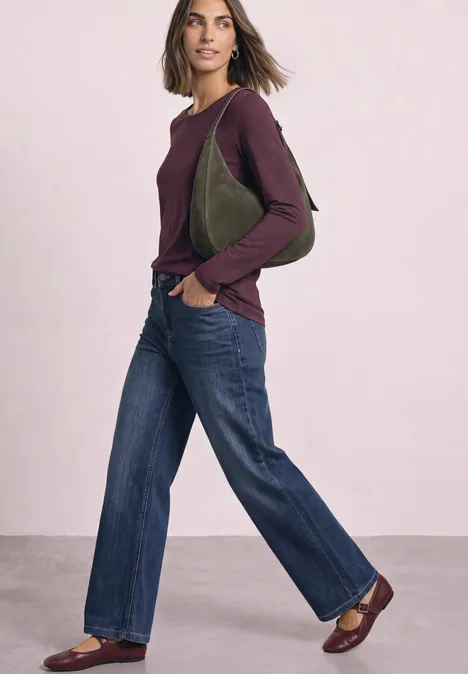 T-shirt basique à manches longues, couleur unie rustic rouge Femme en jean large, haut à manches longues bordeaux, sac vert à l’épaule et mocassins bruns sur fond clair.
