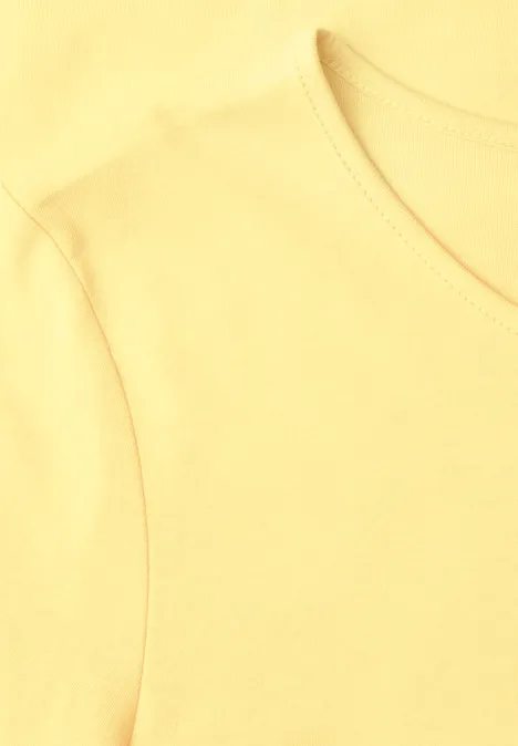 Helles gelbes T-Shirt, Nahaufnahme von Kragen und Schulterbereich.