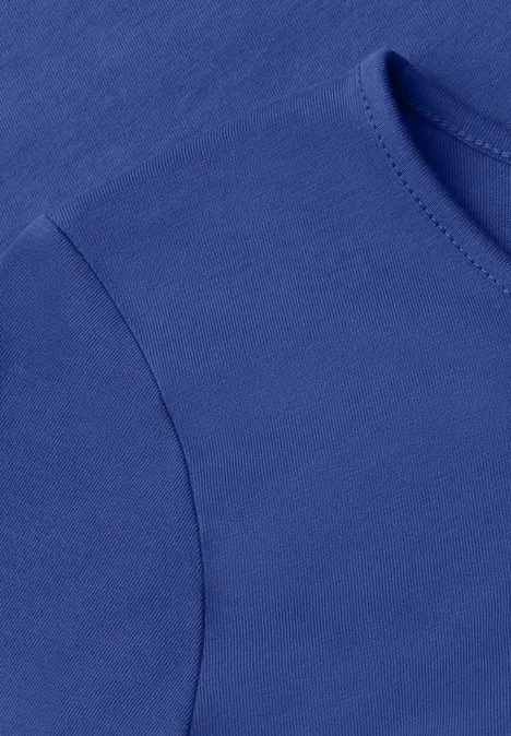 Nahaufnahme eines einfarbigen blauen T-Shirts mit Rundhalsausschnitt und Naht am Ärmelansatz.