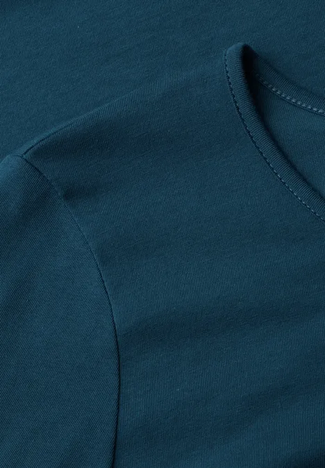 Dunkeltürkises T-Shirt aus Baumwollstoff, Detailaufnahme von Ärmel und Halsausschnitt.