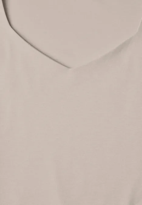 Gros plan sur un tissu beige clair avec une encolure en V.
