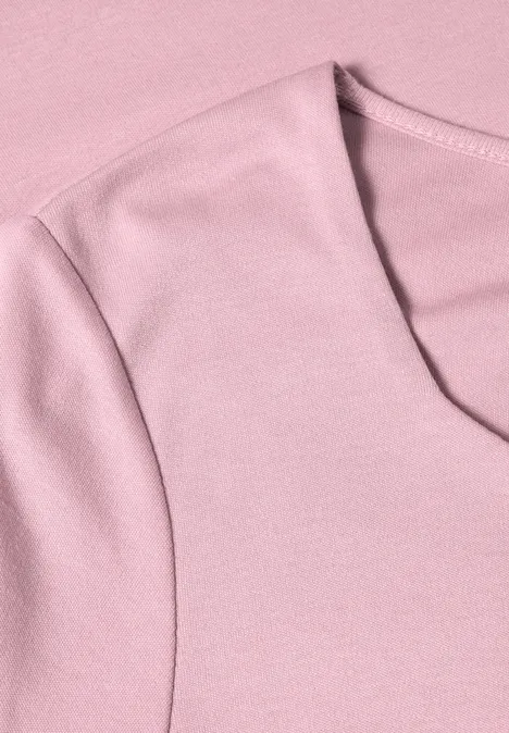 Close-up van een lichtroze katoenen t-shirt met ronde hals en schoudernaden.