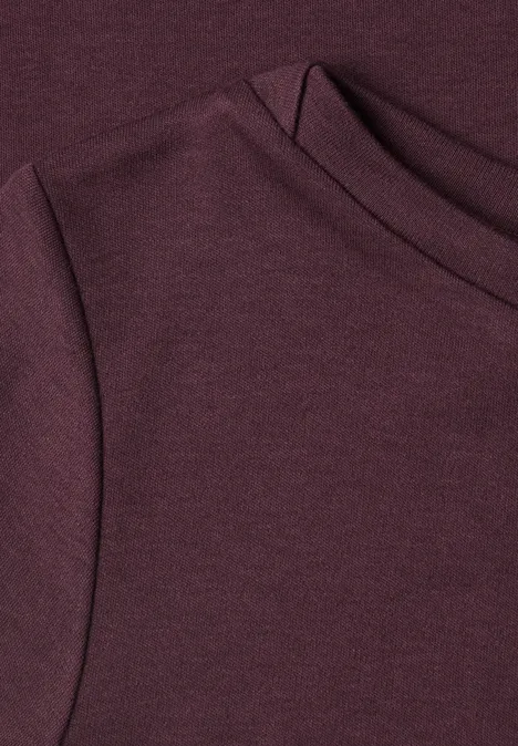 Nahaufnahme eines burgunderfarbenen Strickoberteils mit Rundhalsausschnitt