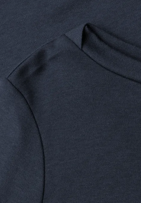Zbliżenie na granatowy t-shirt z widocznym szwem na ramieniu i przy kołnierzu