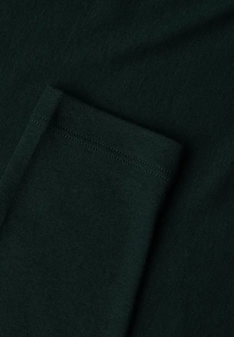 Close-up van een opgestikte zak van donker groen, gestructureerd textiel.