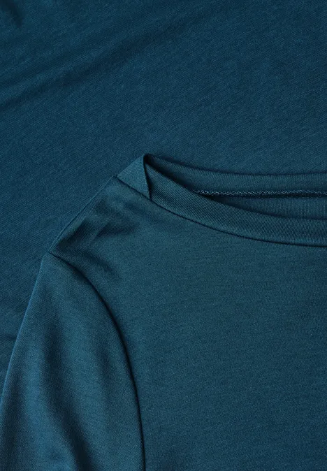 Close-up van een petrolblauw T-shirt met ronde hals en zachte stofstructuur.