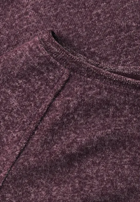 Nahaufnahme eines bordeauxfarbenen Strickstoffs mit sichtbarer Naht und weicher, melierter Textur.