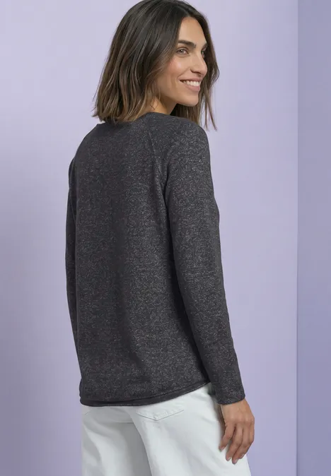 Langarm Shirt mit Rundhals und Rollkante armor grey mel. Frau mit dunkelgrauem Langarmpullover und weißer Hose blickt lächelnd über die Schulter vor lilafarbenem Hintergrund.