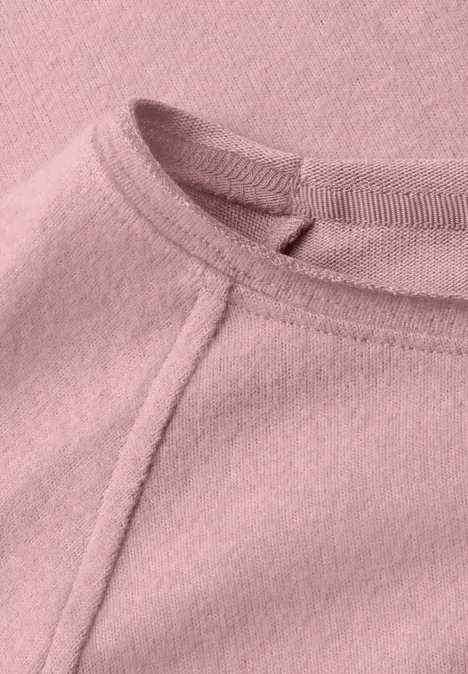 Nahaufnahme eines rosa Fleece-Oberteils mit sichtbarer Naht am Rundhalsausschnitt.