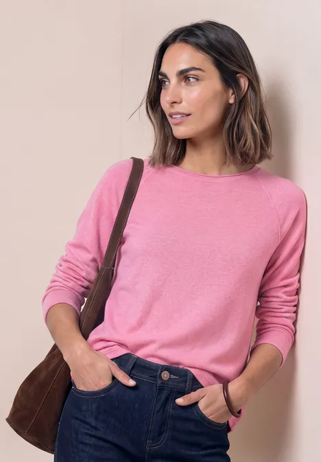 Langarm Shirt mit Rundhals und Rollkante warm blush mel. Frau in rosa Pullover und blauen Jeans mit brauner Umhängetasche vor hellbeigem Hintergrund.