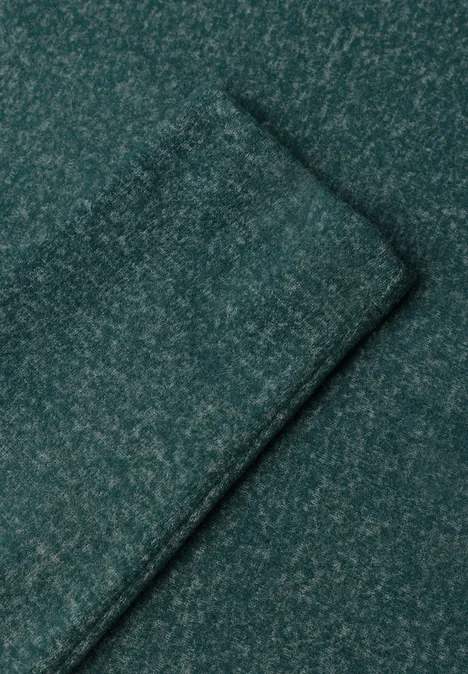 Close-up van een donkergroen, gemêleerd gebreid stof met zichtbare naad.