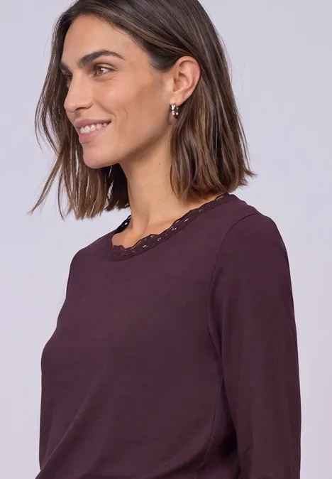 Langarm Shirt mit Rundhals und Spitze rustic rouge Frau mit kastanienbraunem, langärmligem Top mit Spitzenbesatz lächelt seitlich.