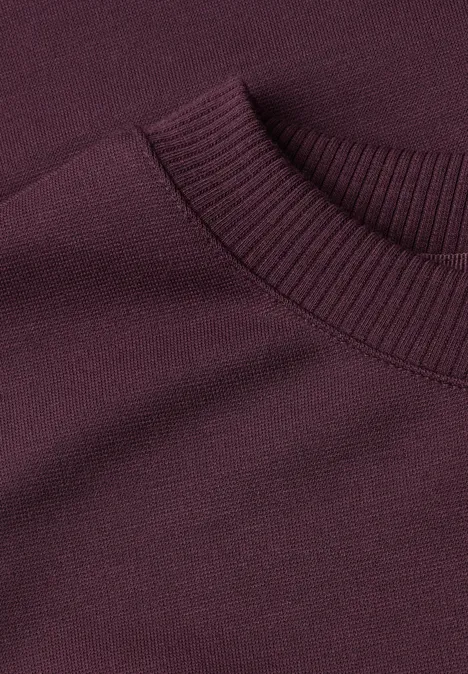 Ausschnitt eines dunkelvioletten Pullis, engmaschig gestrickt, gerippter Rundhalsausschnitt