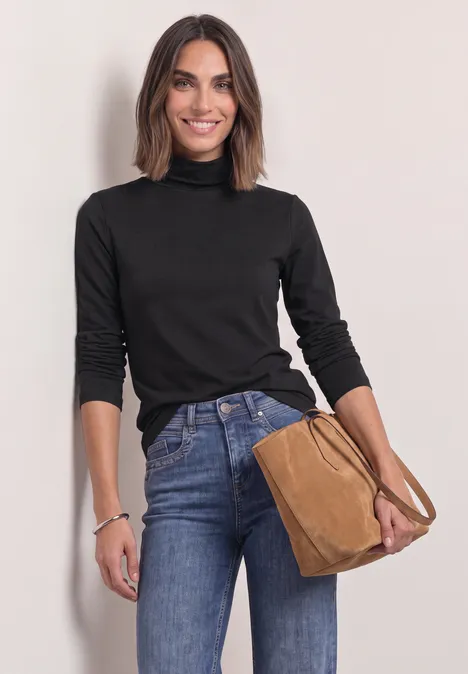 Langarm Shirt in Unifarbe mit Rollkragen Black Eine lächelnde Frau in schwarzem Rollkragenpullover und Jeans, hält eine braune Handtasche.
