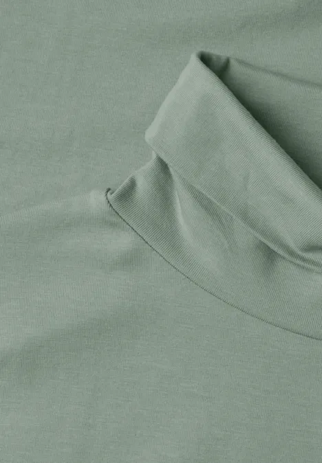 Hellgrüner Rollkragenpullover aus weichem Stoff, flach liegend.