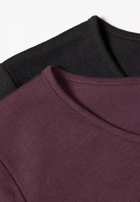 Zwei Rundhals-T-Shirts, eines in Schwarz, eines in Aubergine, nebeneinander angeordnet.