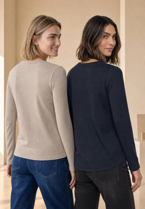 Twee vrouwen van achteren, gekleed in lange mouwtruien en jeans in neutrale kleuren.