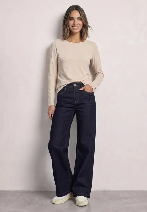 Lot de 2 t-shirts à manches longues et col rond darkest blue/clay sand Frau steht vor heller Wand und trägt helles Langarmshirt mit dunkler, weiter Jeans