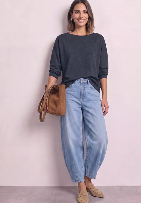T-shirt à manches longues avec ourlet élastiqué darkest blue mel. Femme en pull gris, jean ample, mocassins beiges et sac marron, posant devant un fond clair.