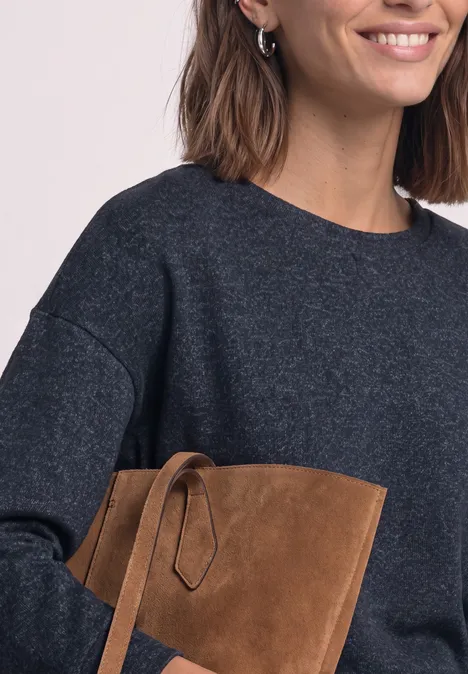 T-shirt à manches longues avec ourlet élastiqué darkest blue mel. Femme en pull gris foncé souriante tenant une pochette en daim marron.