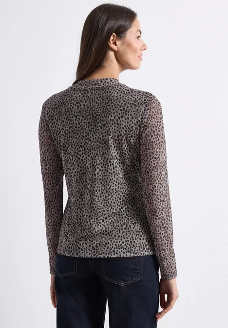Mesh-Shirt met lange mouwen en col Black Frau von hinten in schwarzem, transparentem, langärmligem Leoparden-Shirt und blauer Jeans, Gesicht seitlich gedreht.