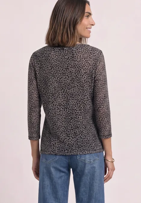 Frau von hinten in Jeans und 3/4-Arm Shirt mit dezentem Leopardenmuster.