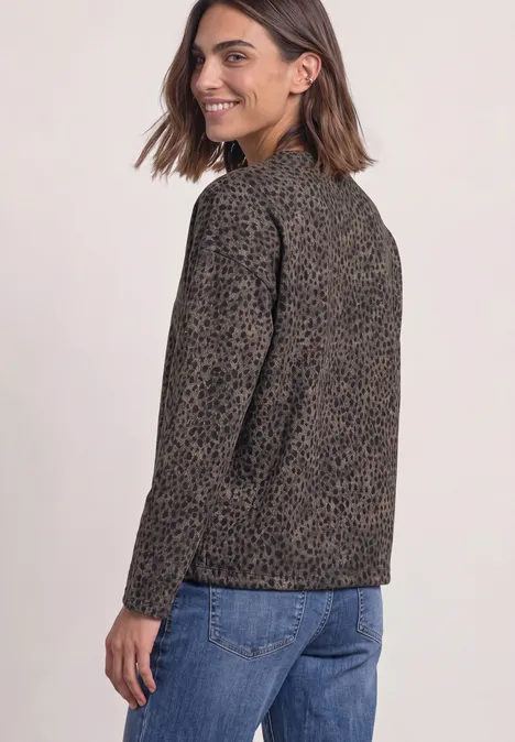 Shirt met lange mouwen, ronde hals en patroon Black Eine lächelnde Frau in Leo-Jacke und Jeans, seitlich zum Betrachter gedreht.