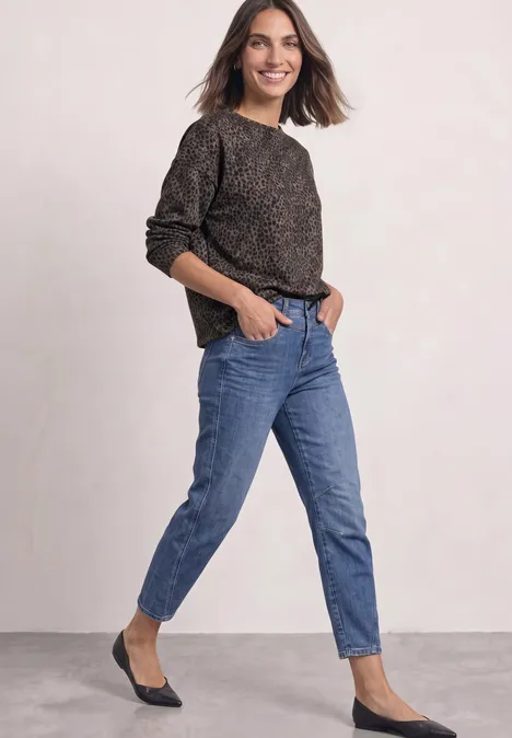 Shirt met lange mouwen, ronde hals en patroon Black Frau trägt lässiges Outfit aus schwarzem Pullover, blauen Jeans und schwarzen Ballerinas.