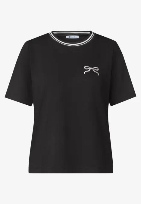 Schwarzes T-Shirt mit kurzen Ärmeln und kleinem Schleifchen auf der Brust.