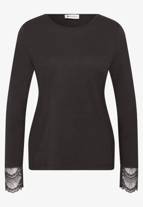 Schwarzes Langarmshirt aus feinem Stoff mit eleganten Spitzenbesätzen an den Ärmelabschlüssen.