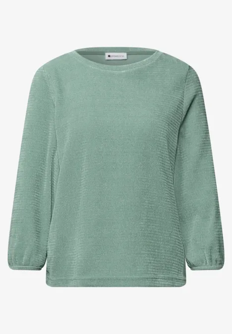 Hellgrüner Pullover mit feinem Strickmuster und lockerer Passform.